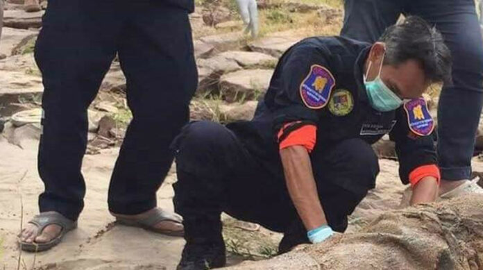 A rescue worker examines a body found Dec. 29 in the Mekong River in Nakhon Phanom city.