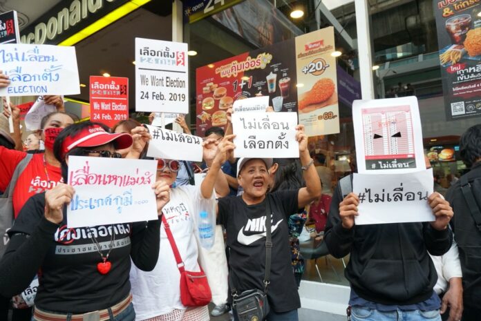 Protesters hold placards demanding the election be held on Feb. 24 at a rally Tuesday near the Ratchaprasong Intersection in Bangkok.