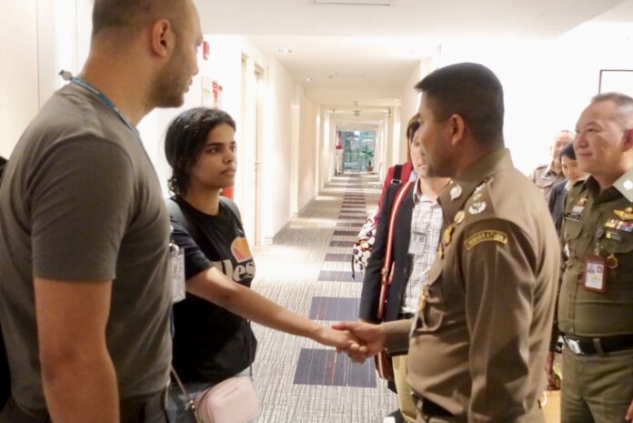 Rahaf Alqunun shakes hand with immigration chief Surachate Hakparn, at right, Monday at Bangkok's Suvarnabhumi Airport. Photo: Immigration Bureau