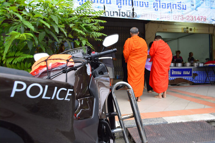 Police accompany monks as they collect alms Sunday in Yala province.