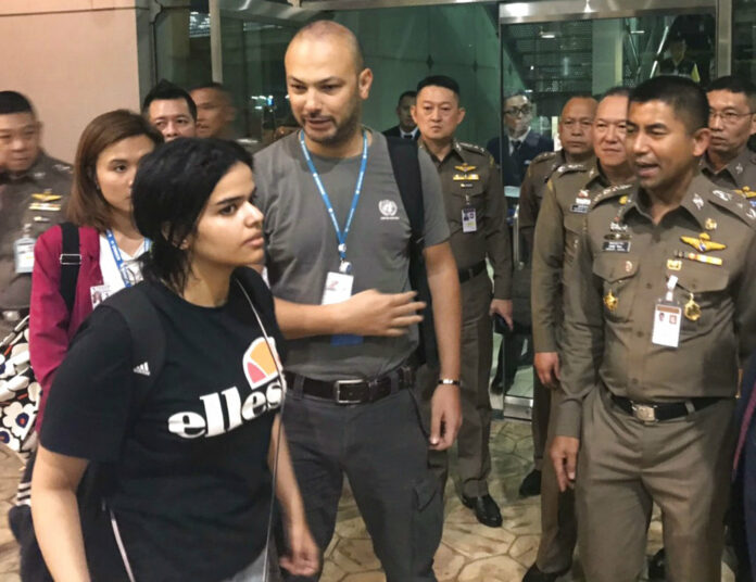 Rahaf Mohammed Alqunun, at left, walks by Thai immigration police chief Maj. Gen. Surachate Hakparn, at right, on her way out of Suvarnabhumi Airport on Monday in Bangkok. Photo: Immigration Bureau Police / Courtesy