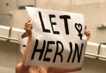 Aussies Go Topless to Support Saudi Runaway A woman protester marches Thursday with a sign outside the building housing the Saudi consulate in Sydney. Image: Australia Broadcast Corporation via AP
