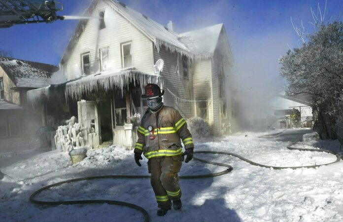 A firefighter walks past an ice-encrusted home after an early morning house fire Wednesday, Jan. 30, 2019 in St. Paul, Minnesota. Photo: Jean Pieri / Associated Press