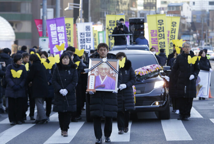 A mourner with a portrait of the deceased Kim Bok-dong, a former South Korean sex slave, marches toward the Japanese Embassy during her funeral ceremony Friday in Seoul, South Korea. Photo: Ahn Young-joon / Associated Press