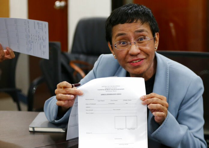 Maria Ressa shows an arrest form after being arrested by National Bureau of Investigation agents in a libel case Wednesday, Feb. 13, 2019 in Manila, Philippines. Photo: Bullit Marquez / Associated Press