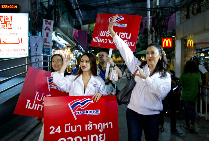 Pauline Ngarmpring, right, a transgender person and a prime minister candidate, and Namklenginarin, center, a candidate for the parliament, both representing the Mahachon party for the upcoming Thai general election, greet people Wednesday during an election campaign in Bangkok. Photo: Gemunu Amarasinghe / Associated Press