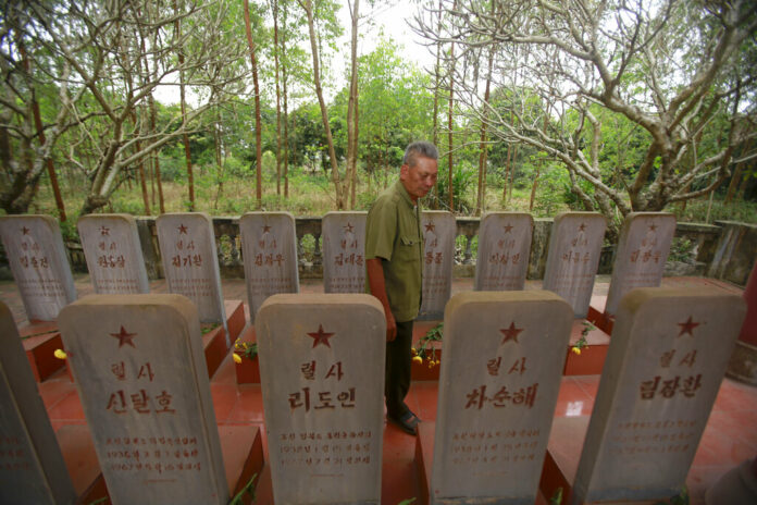 War veteran Duong Van Dau walks in between a row of headstones Saturday at a memorial for North Korean fallen pilots in Bac Giang province, Vietnam. Photo: Hau Dinh / Associated Press