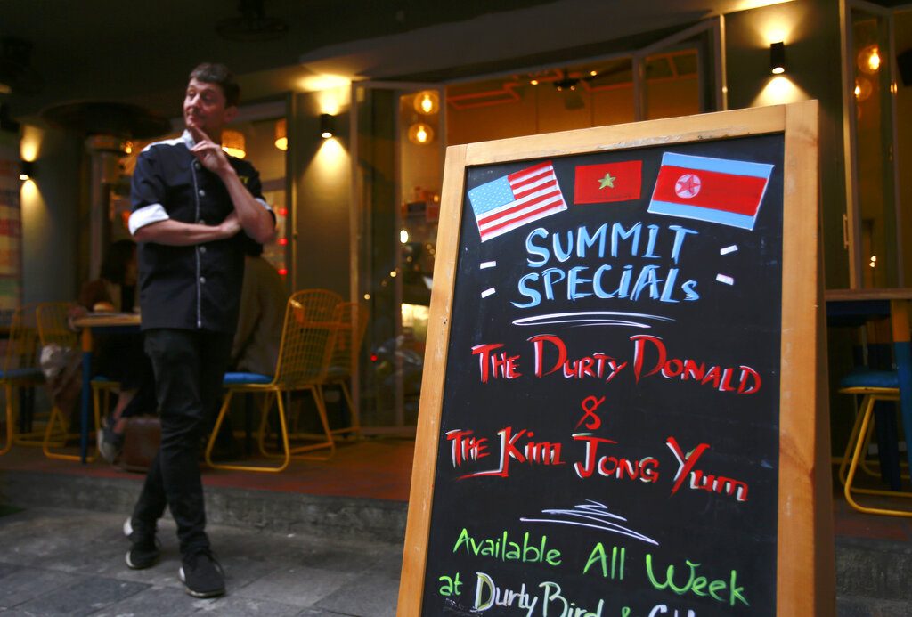 Durty Bird restaurant owner Colin Kelly stands Sunday next to a menu offering Trump-Kim summit special burgers in Hanoi, Vietnam. Photo: Hau Dinh / Associated Press