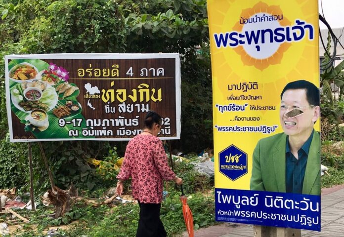 A woman walked past a damaged campaign poster of People’s Reform Party