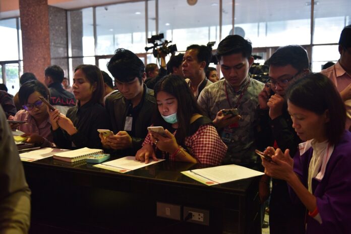 Reporters take photos of a statement by the Constitutional Court declaring that it has accepted a request to disband Thai Raksa Chart Party.