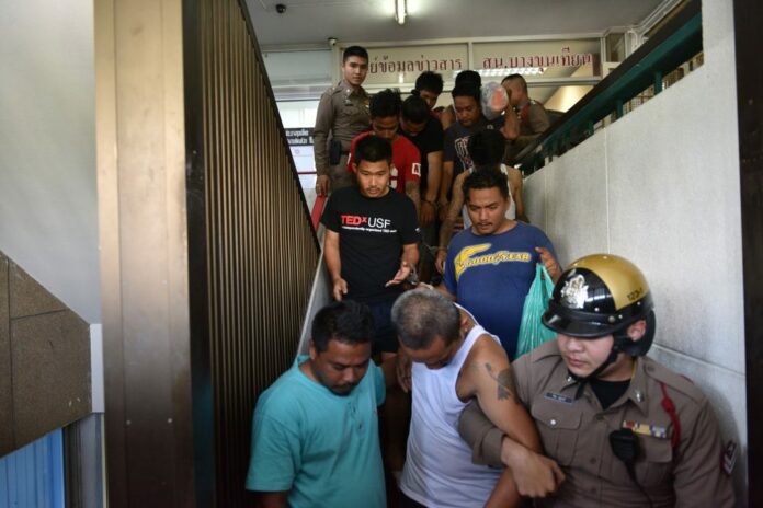 Police lead suspects in the attack on a Bangkok temple school Tuesday out of the Bang Khun Thian police station.
