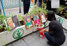 Wife Accuses Junta Behind Murder of Missing Republican Activist A mourner lays flower at a commemoration event Feb. 2 in Bangkok for missing activist Surachai Danwattananusorn, pictured in the center, and two of his aides whose bodies were found in the Mekong River.