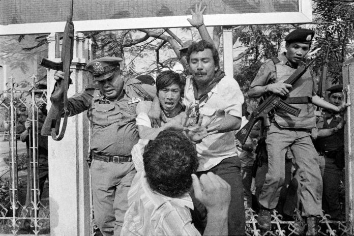 A man raises his fist to punch a captured student activist during a police crackdown at Thammasat University on Oct. 6, 1976. Witnesses said 'Scum of the Earth' was played during the massacre.