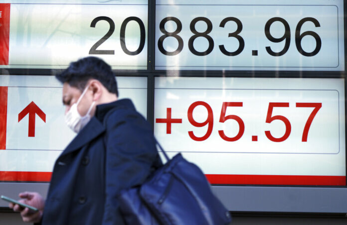 A man walks past an electronic stock board showing Japan's Nikkei 225 index at a securities firm Feb. 4 in Tokyo. Photo: Eugene Hoshiko / Associated Press