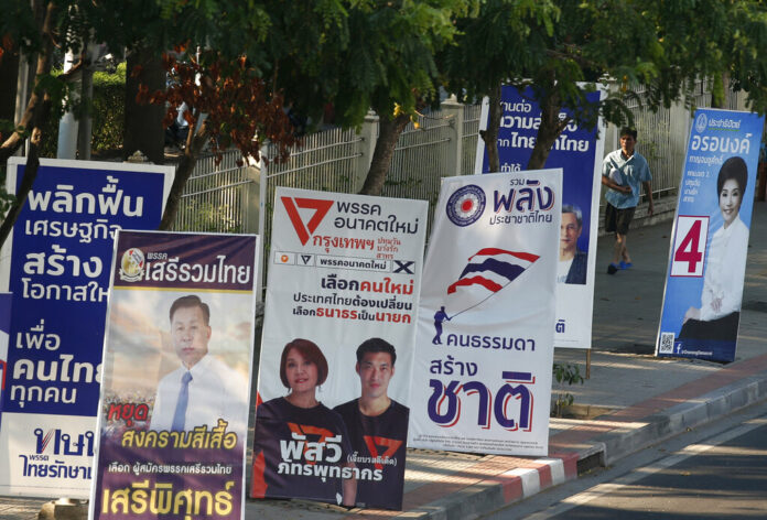 In this March 12, 2019, photo, a pedestrian walks past the election campaign posters in Bangkok, Thailand. Photo: Sakchai Lalit / Associated Press