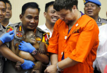 Indonesia Says Arrested Russian Smuggled Orangutan, Lizards Denpasar police chief Ruddi Setiawan, center left, holds a two-year-old male orangutan as Russian Andrei Zhestkov, center right, stands during a Monday press conference in Bali, Indonesia. Photo: Firdia Lisnawati / Associated Press