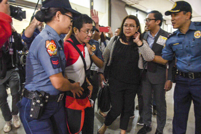 In this photo released by Rappler, Rappler CEO and Executive Editor Maria Ressa, second left, is escorted by police after being arrested upon her arrival at Manila’s International Airport, Philippines Friday March 29, 2019. Photo: Leanne Jazul / Rappler via Associated Press