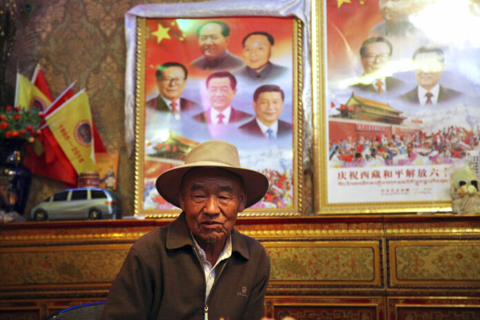 In this Sept. 17, 2015 file photo, Dronjie, 69, sits in his home near two posters displaying the images of current and former leaders of China in Lhasa, capital of the Tibet Autonomous Region of China. Photo: Aritz Parra / Associated Press
