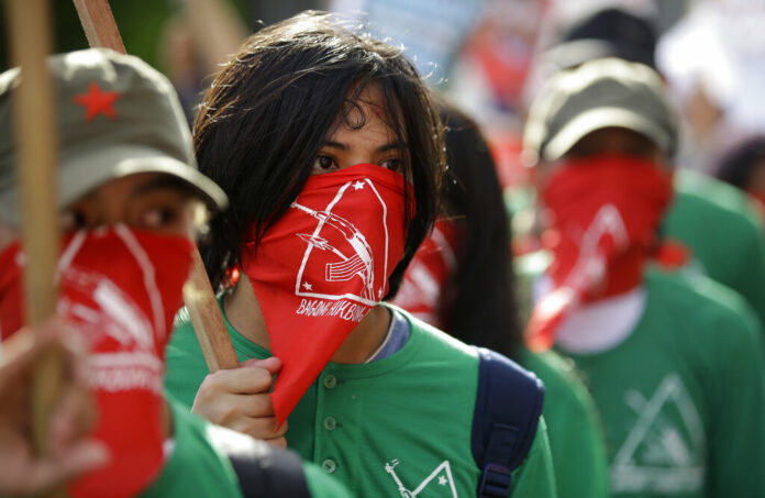 In this March 25, 2019, file photo, masked members of the outlawed National Democratic Front of the Philippines, the umbrella organization of the Philippine communist movement, listen during a demonstration in Manila, Philippines. Photo: Aaron Favila / Associated Press