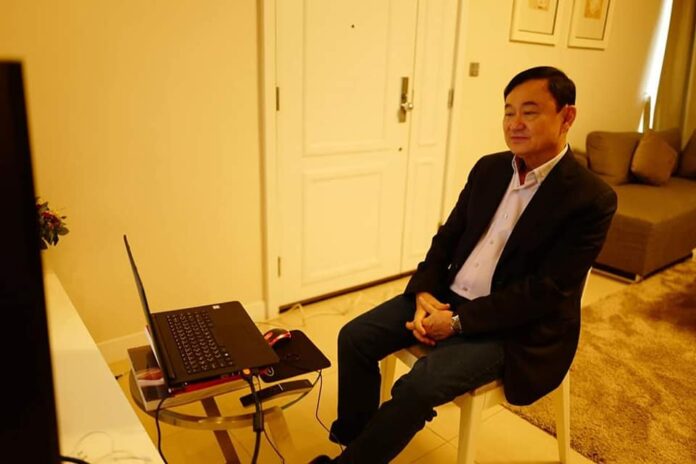 In a photo released by his aides, Thaksin Shinawatra on Sunday watches a livestream of his daughter’s engagement ceremony in Bangkok from an undisclosed location.