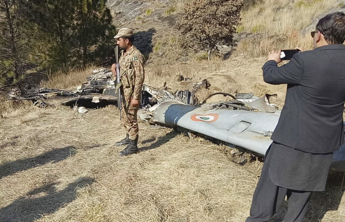 A Pakistani soldier stands guard near the wreckage of an Indian plane shot down by the Pakistan military on Wednesday, in Hurran, near the Line of Control in Pakistani Kashmir. Photo: Abdul Razzaq / Associated Press