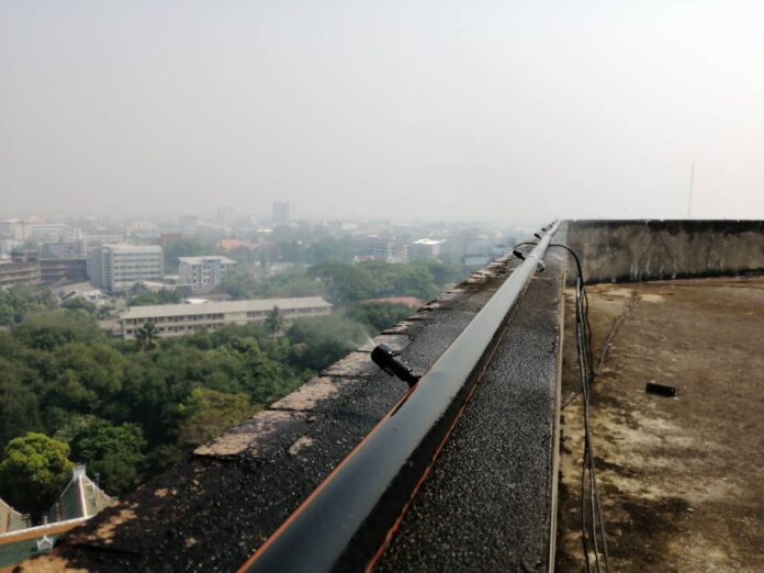 A nozzle sprays water from atop a building Monday in Chiang Mai as the city is covered with smog.