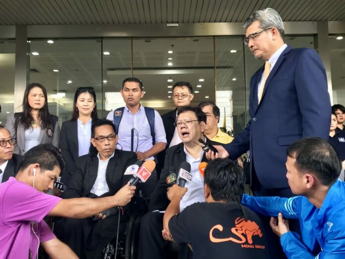 Manit Inpim, left in wheelchair, and Theerayut Sukonthawit, right in wheelchair, speak to reporters Monday in front of the Administrative Court.