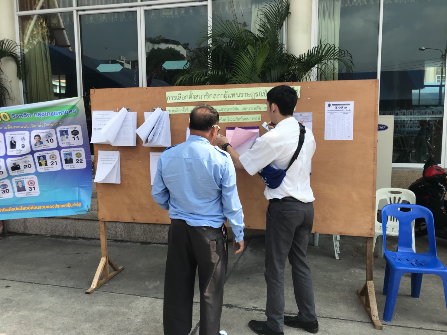 Polling station worker Tossaporn Noomnok, in white, at Wat Noi Nang Hong in Bangkok.