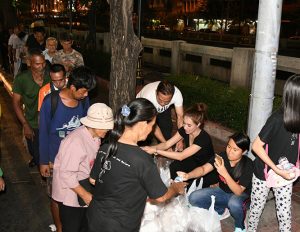 Homeless people queue up for free meals handed out Friday night in the parking lot of Hua Lamphong Station, which a foundation staffer says they receive daily from private organizations.