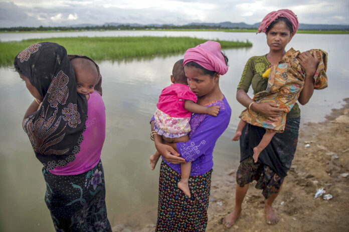 In this Oct. 18, 2017, file photo, Rohingya Muslim women, who crossed over from Myanmar into Bangladesh, stand holding their sick children after Bangladesh border guard soldiers refused to let them journey towards a hospital and turned them back towards the zero line border in Palong Khali, Bangladesh. Photo: Dar Yasin / Associated Press