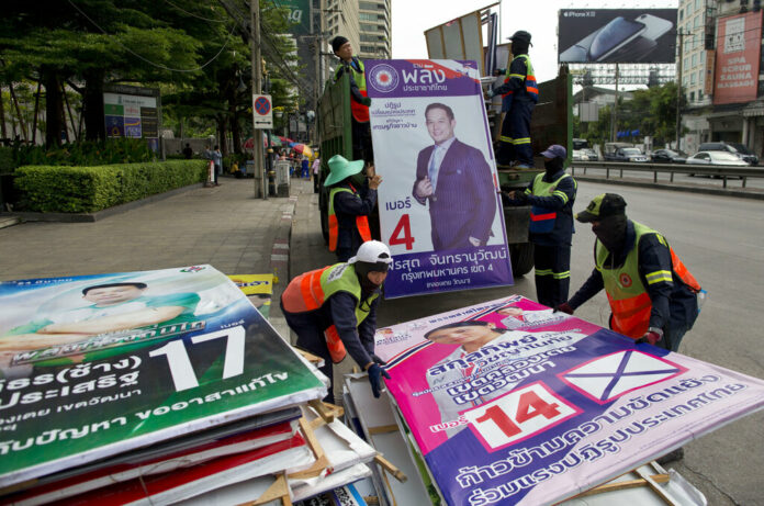 In this March 27, 2019, file photo, workers load campaign billboards displayed to promote candidates for a general election into a truck in Bangkok, Thailand. Photo: Gemunu Amarasinghe / Associated Press