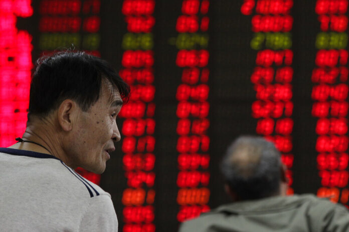 Investors monitor stock prices Monday at a brokerage house in Beijing. Photo: Andy Wong / Associated Press