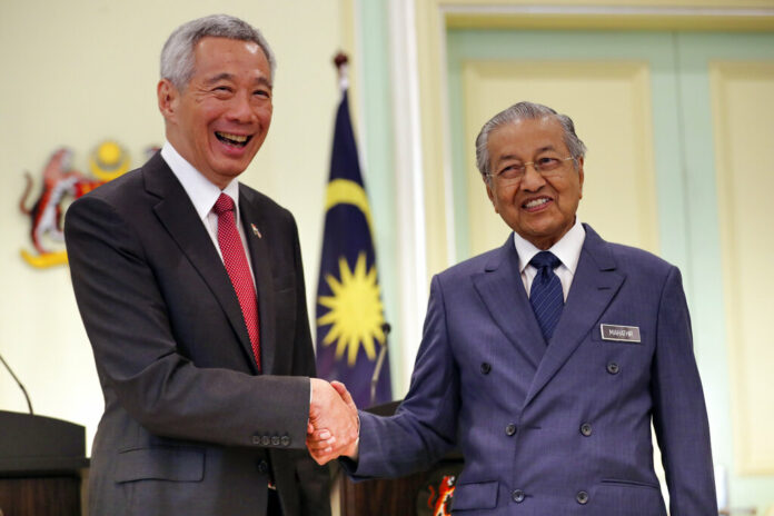 Malaysian Prime Minister Mahathir Mohamad, right, shakes hands with Singaporean Prime Minister Lee Hsien Loong Tuesday after a press conference in Putrajaya, Malaysia. Photo: Vincent Thian / Associated Press