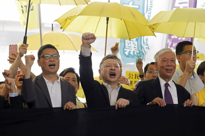 Chan Kin-man, Benny Tai, Chu Yiu-ming Occupy Central leaders, from left, Chan Kin-man, Benny Tai and Chu Yiu-ming chant slogans before entering a court in Hong Kong, Wednesday, April 24, 2019. Photo: Kin Cheung / Associated Press