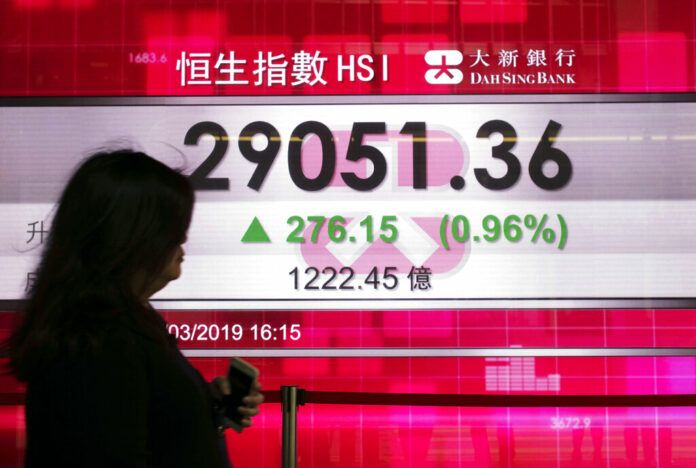 A woman walks past an electronic board showing Hong Kong share index outside a local bank in Hong Kong, Monday, April 1, 2019. Photo: Vincent Yu / Associated Press