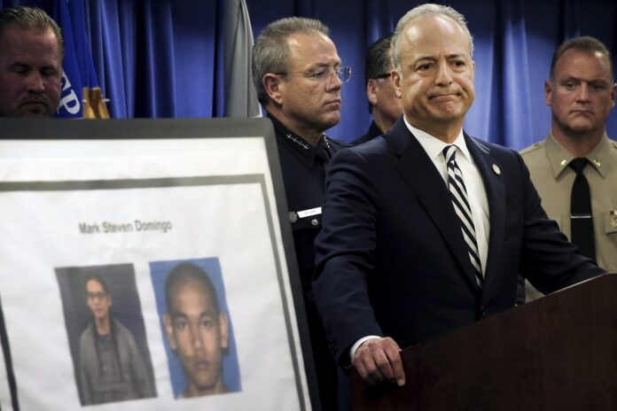 United States Attorney Nick Hanna stands next to photos of Mark Steven Domingo, during a news conference in Los Angeles on Monday, April 29, 2019. (AP Photo/Richard Vogel)