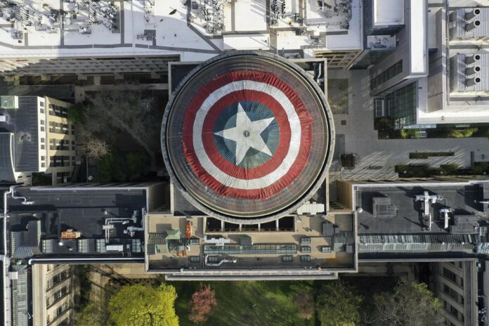 This Sunday, April 28, 2019 photo provided by Raymond Huffman shows Massachusetts Institute of Technology's signature Great Dome draped with a giant cloth version of Captain America's red, white and blue shield, in Cambridge, Mass.(Raymond Huffman via AP)