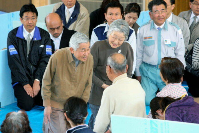A file photo of Japanese Emperor Akihito and Empress Michiko, kneeling down and smiling at people at an earthquake evacuation shelter in Chiba Prefecture. Image: Associated Press