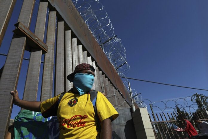 Migrants gather at the Mexico-U.S. border after getting past a line of Mexican police at the Chaparral crossing in Tijuana, Mexico, Sunday, Nov. 25, 2018, as they try to reach the U.S.