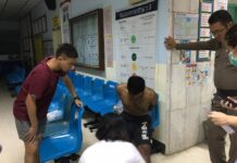Chonburi Man Arrested Over Alleged Rape-Murder of German Tourist Ronnakorn Romreun, sitting at center, in a police station after he was arrested and accused of raping and murduring a German tourist Sunday on Koh Sichang, Chonburi province.