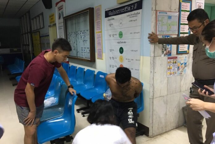 Ronnakorn Romreun, sitting at center, in a police station after he was arrested and accused of raping and murduring a German tourist Sunday on Koh Sichang, Chonburi province.