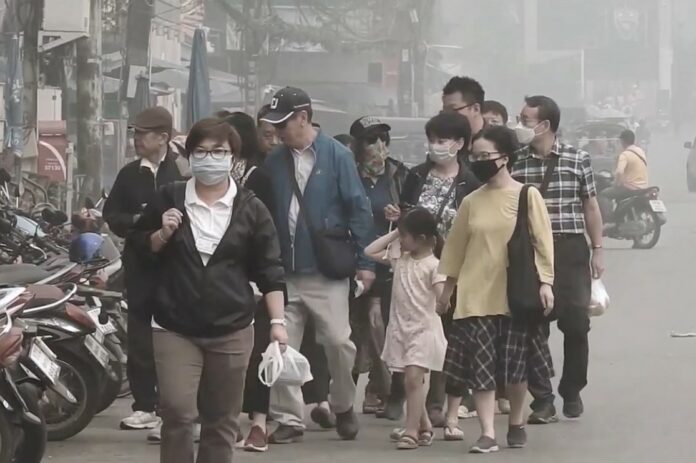 People are seen wearing face masks as they walk Monday in Chiang Rai’s Mae Sai district.
