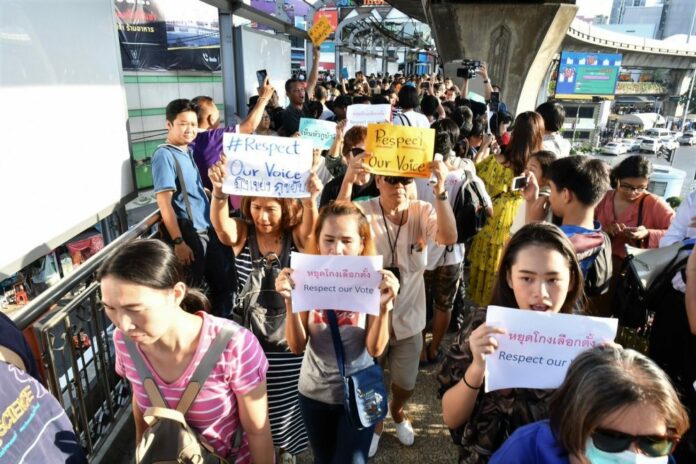 Protesters hold signs during a demonstration Sunday in Bangkok demanding the Election Commission be impeached.