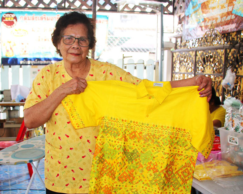 Sawaeng Suwadit, of the Talad Chalong community in Sriracha district holds up a yellow shirt her craft group made for Songkran sales.