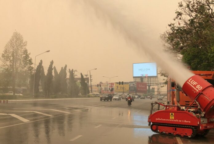 A fire-fighting equipment sprays water onto a street Sunday in Chiang Rai city as heavy smog is seen covering the area.