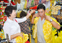 Coronation-Themed Songkran Shirts at the Ready Customers try on yellow Hawaiian shirts at Supak Sawasdee’s shop in Korat.