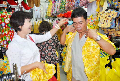 Customers try on yellow Hawaiian shirts at Supak Sawasdee’s shop in Korat.