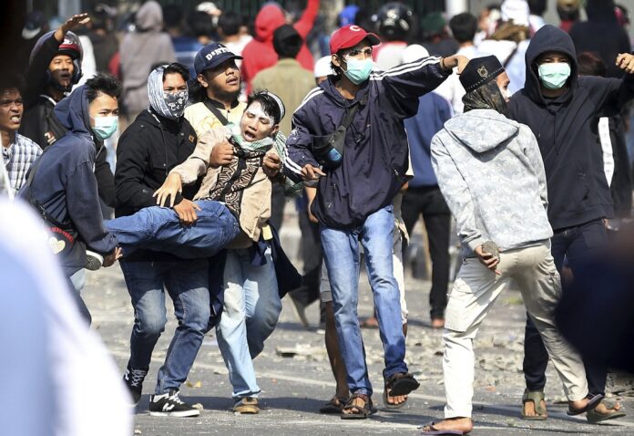 upporters of Indonesian presidential candidate Prabowo Subianto carry an injured man during a clash with Indonesian police in Jakarta, Indonesia, Wednesday, May 22, 2019. (AP Photo/Achmad Ibrahim)