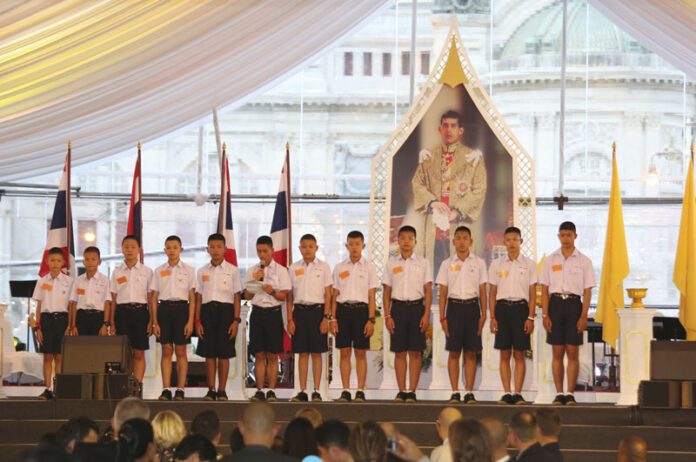 In this Sept. 6, 2018. file photo, members of the Wild Boars, the soccer team that was rescued from a flooded cave, give thanks in front of Thailand King Maha Vajiralongkorn's image during an event titled 