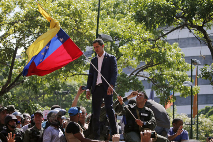 Venezuela's opposition leader and self-proclaimed President Juan Guaido stands before supporters as he addresses them outside La Carlota military air base in Caracas, Venezuela, Tuesday, April 30, 2019. Guaid√≥, accompanied by civilian protesters and a small contingent of heavily armed troops, called Tuesday for the military to rise up and oust socialist leader Nicolas Maduro. Photo: Fernando Llano / AP